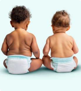 Two babies sitting side-by-side, facing backwards, wearing diapers