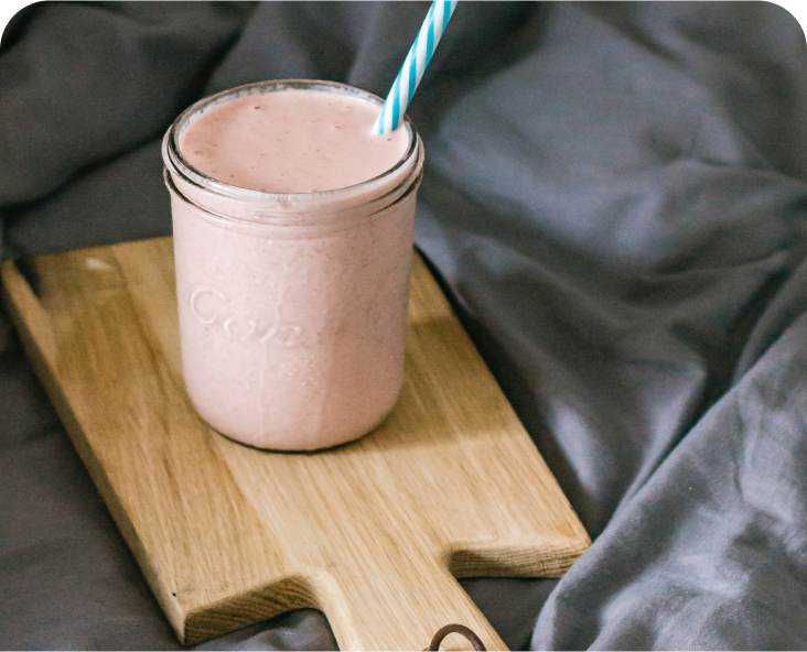 Image of a pink smoothie in a glass jar with straw.