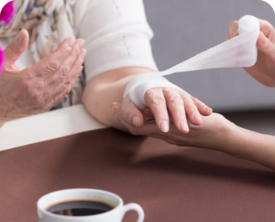 Image of a person bandaging an older woman's hand.