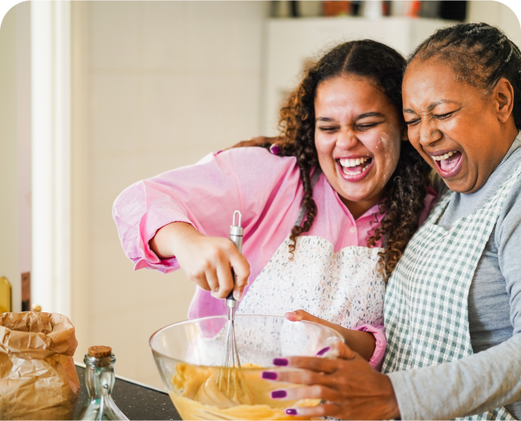 Image of adult mom and her adult daughter cooking in the kitchen.