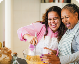 Image of adult mom and her adult daughter cooking in the kitchen.