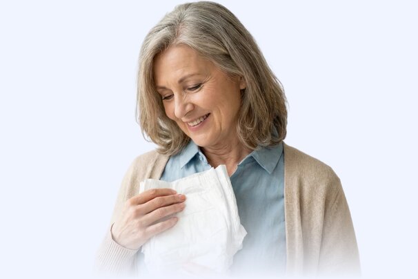 Happy senior woman holding an adult diaper