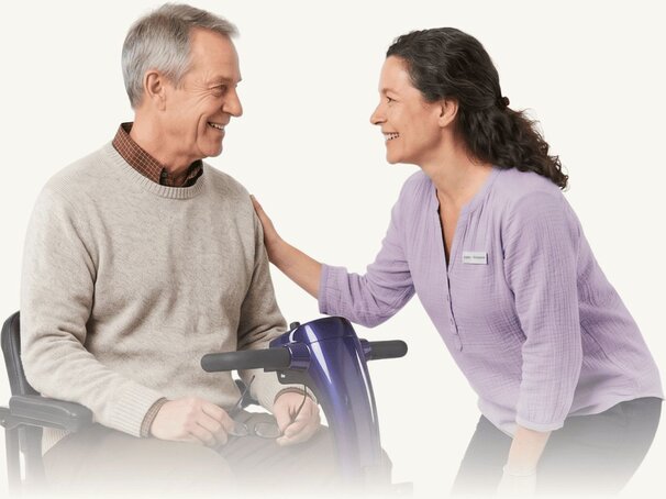 Friendly, professional woman speaking with a relaxed senior man in a mobility scooter.