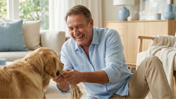 Confident man playing with his dog in the living room