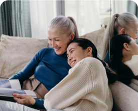 Image of an adult mother and daughter cuddling on a couch.