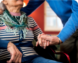 Image of someone assisting an older woman in a wheelchair.