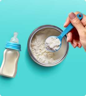 Baby powdered formula being scooped out of a bowl, next to a baby bottle