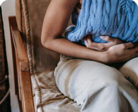 Image of a seated woman cradling her lower abdomen in pain.