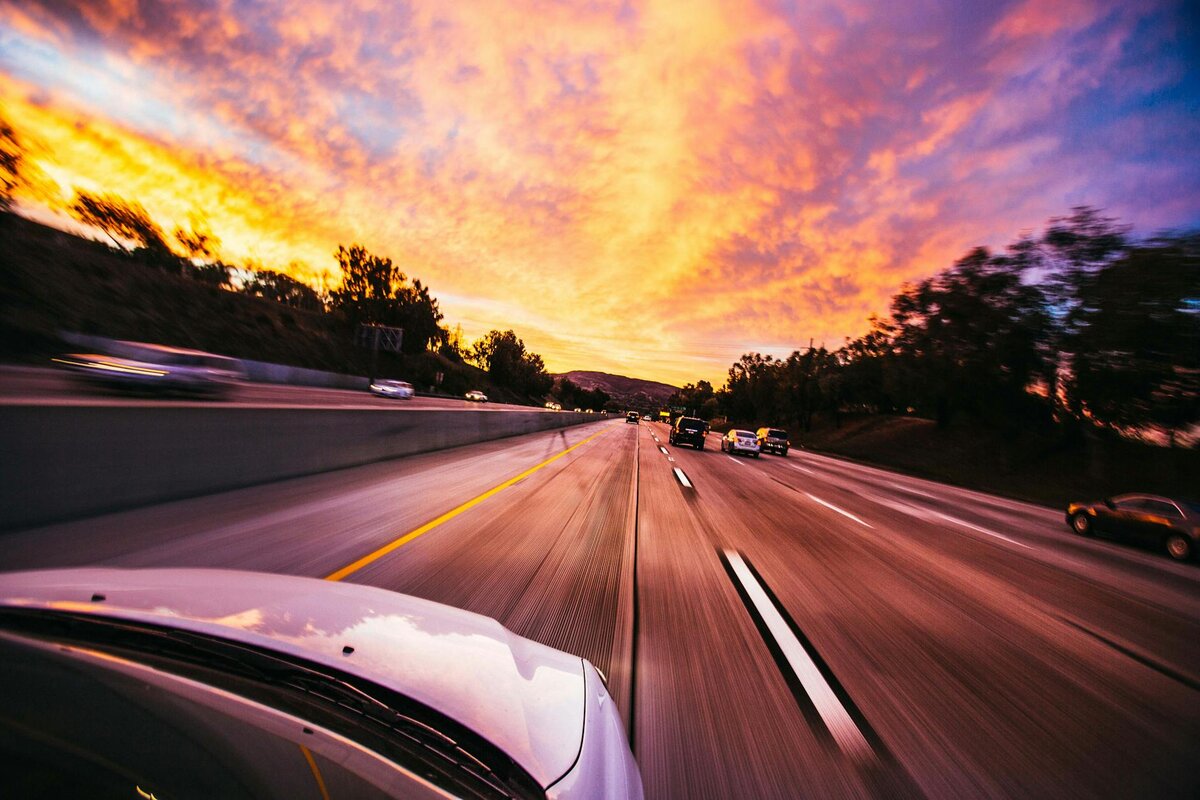 Image of car driving during sunset on highway with other cars