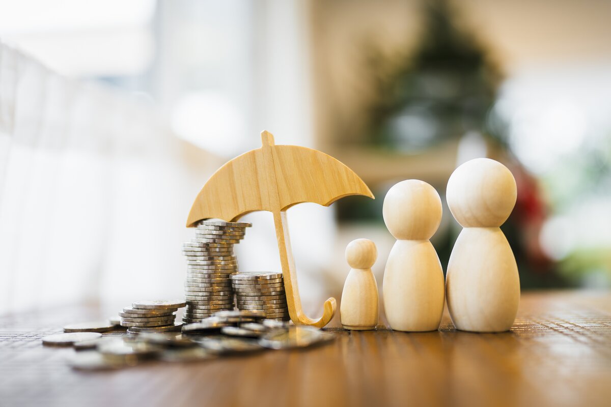 Wooden figurines of family with wooden umbrella protecting coins