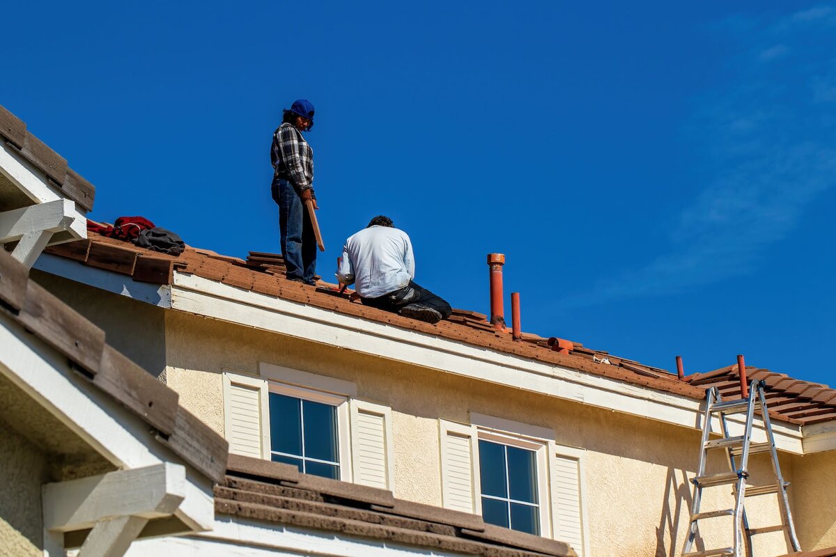 Two roofing workers working on a roof