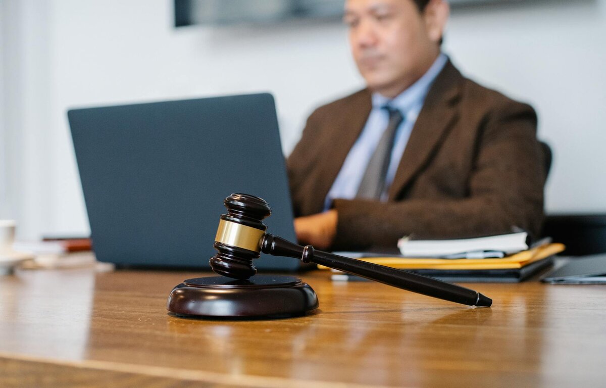 Man in suit on computer with gavel in foreground