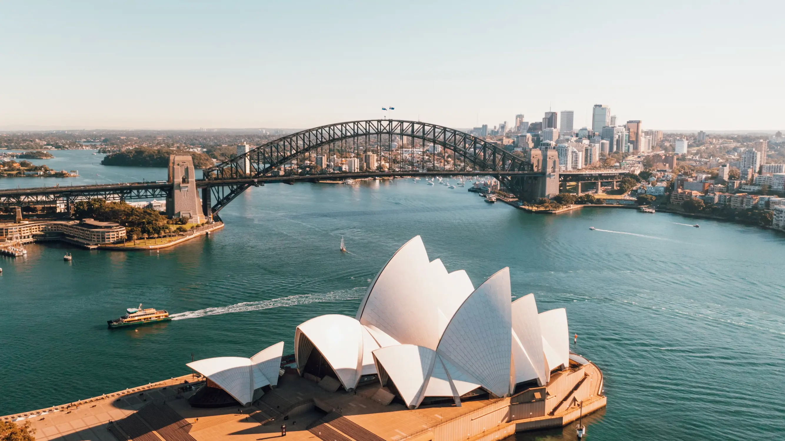 Sydney Opera House and Harbour Bridge with city skyline and ferries on the water