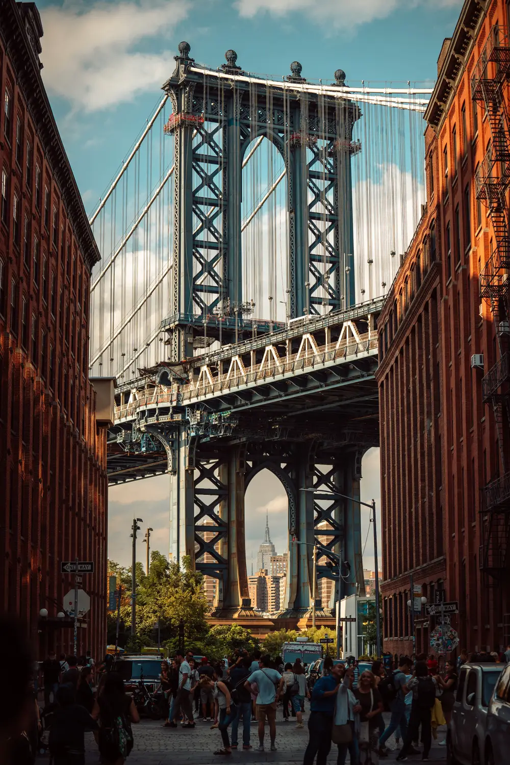 The Manhattan Bridge framed between brick buildings on a cobblestone street in Dumbo, Brooklyn.