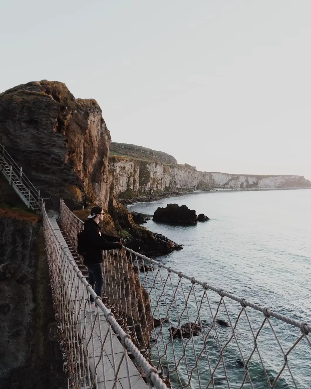 Person standing on a rocky cliffside path overlooking the sea, Ireland.