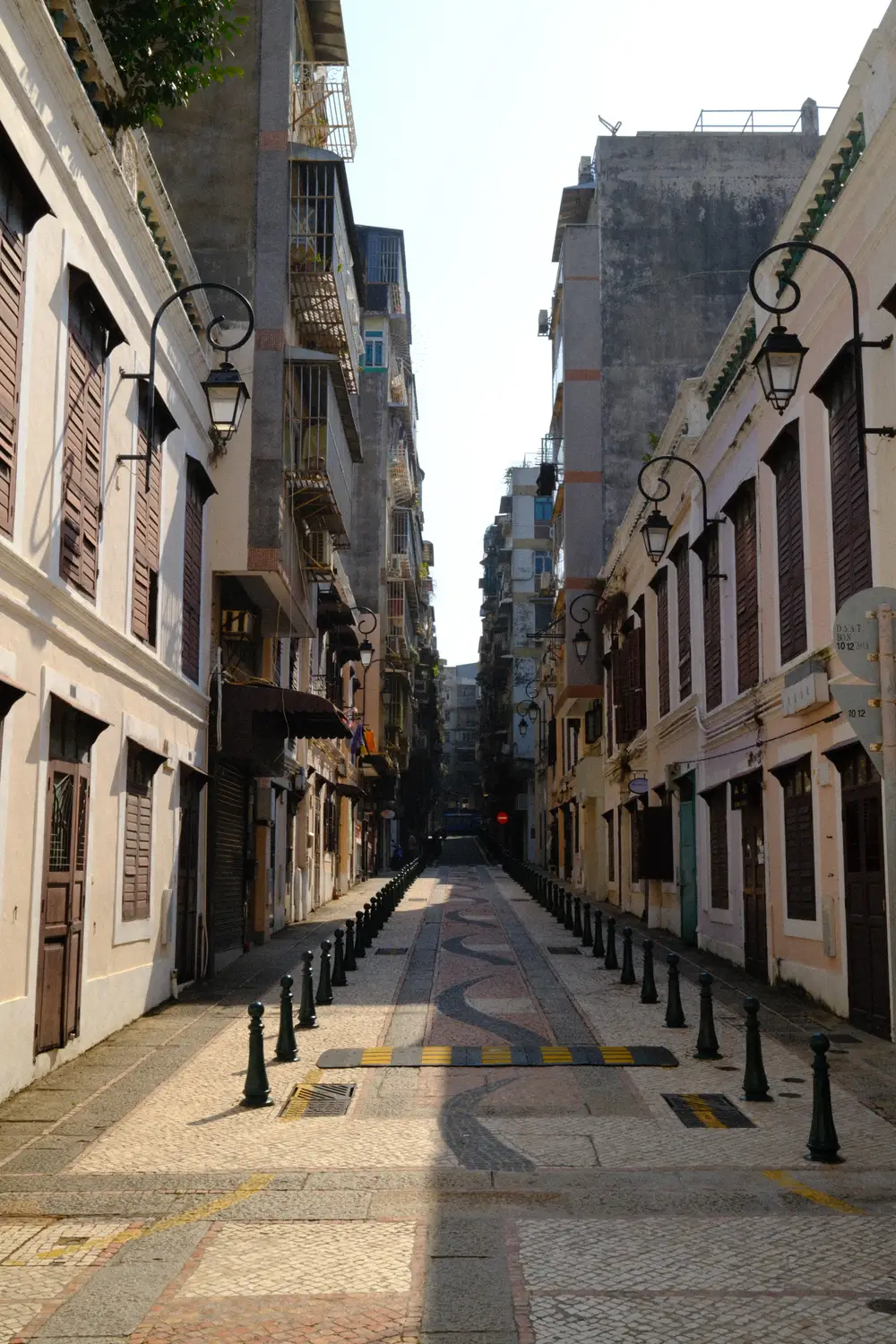 Narrow cobblestone alley between pastel colonial buildings in Macau's old town