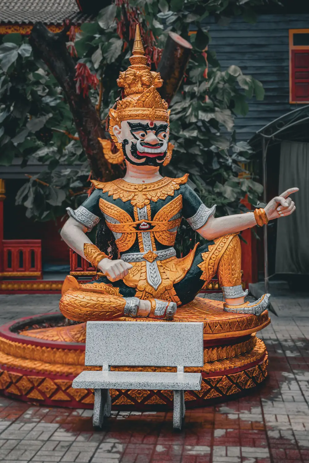Colorful seated guardian deity statue at a Buddhist temple in Laos.