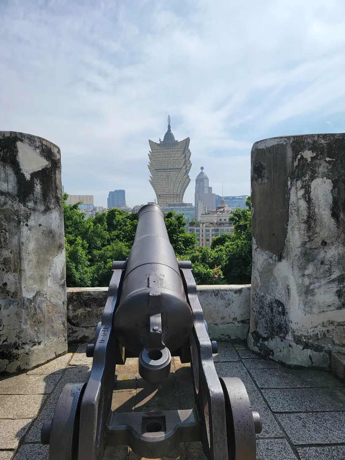 Historic cannon at Fortaleza do Monte overlooking Macau's Grand Lisboa skyline