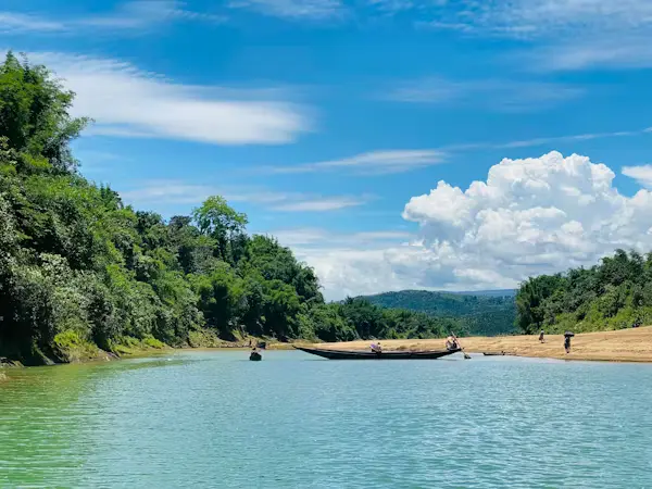 Wooden boats on crystal-clear turquoise river surrounded by lush green hills and sandy banks, Bandarban, Chittagong Hill Tracts, Bangladesh