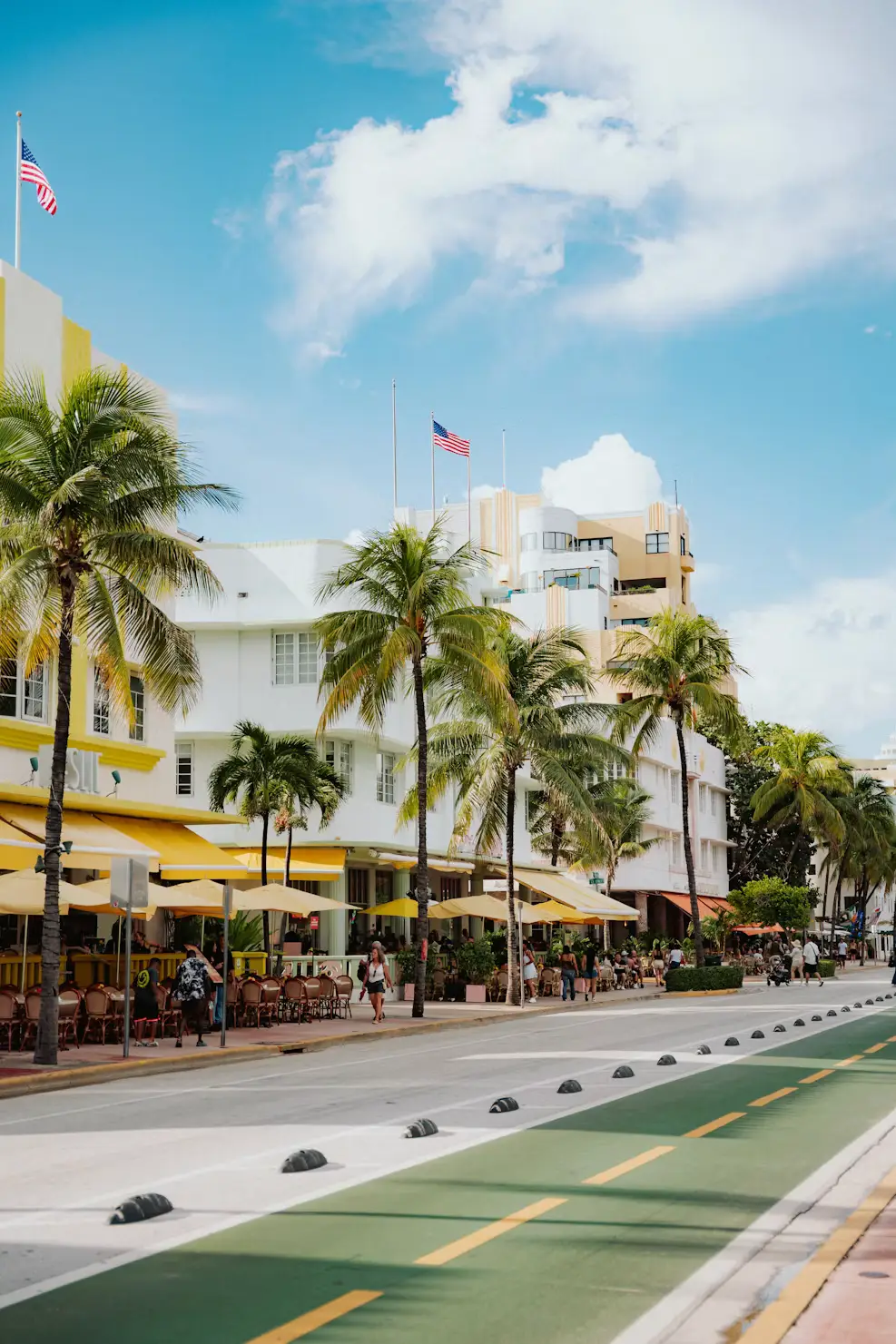 Palm trees and pastel art deco buildings lining a sunny street in Miami's South Beach.