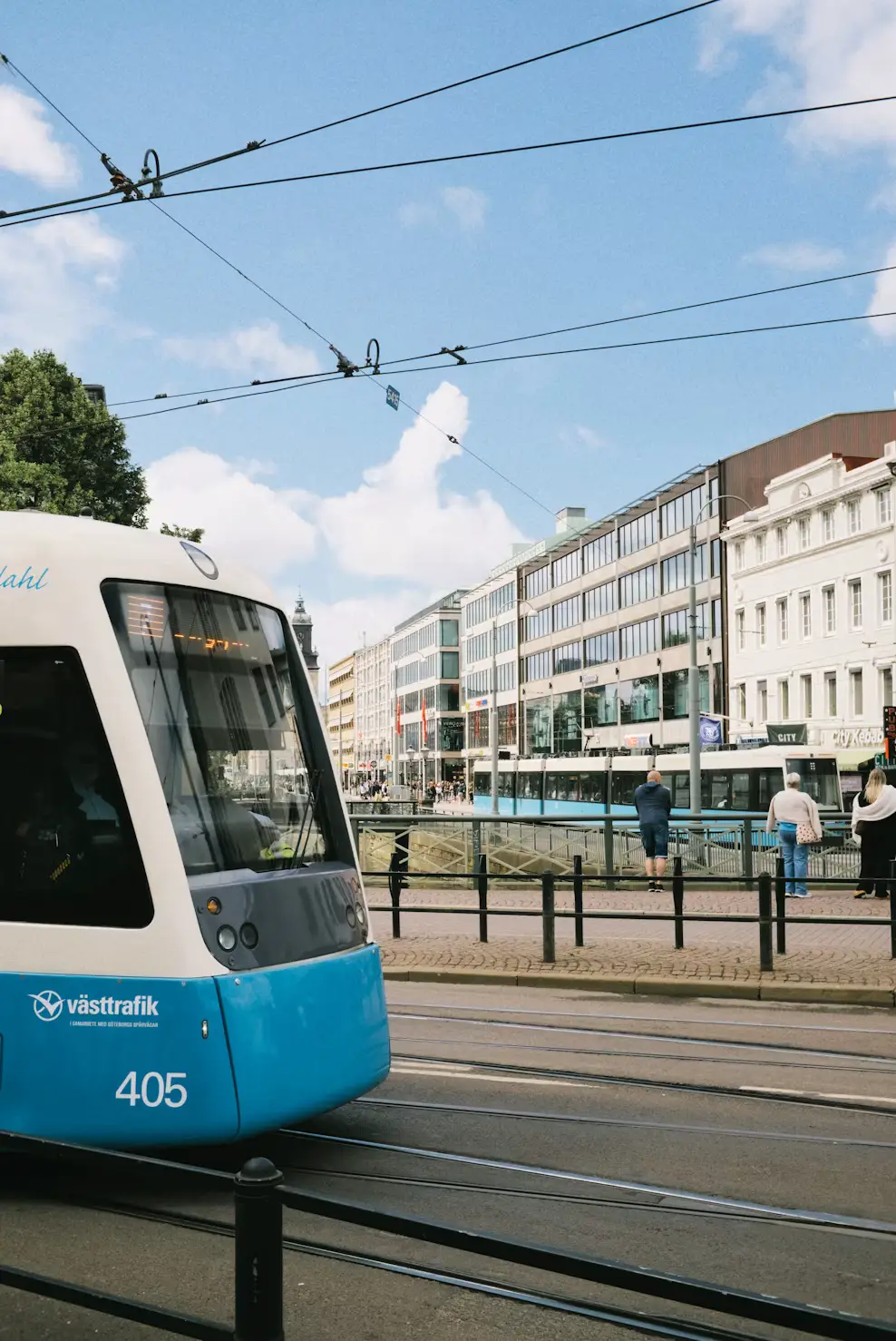 Blue and white tram traveling along a city street lined with buildings.