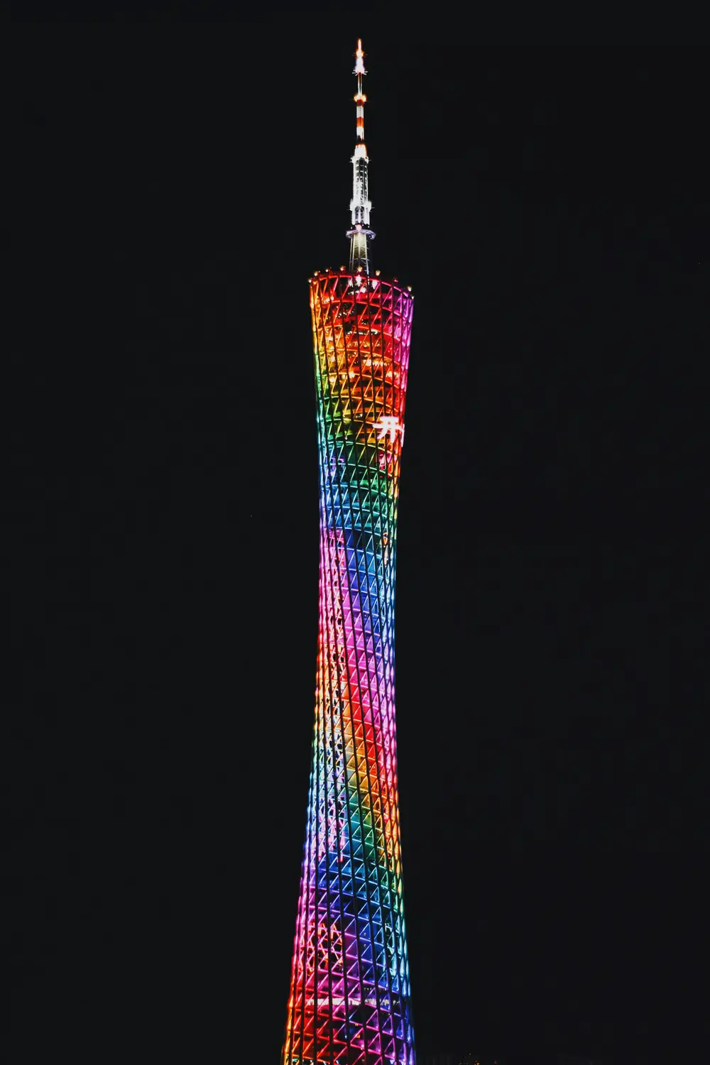 Canton Tower Guangzhou illuminated with rainbow colored LED lights at night against dark sky