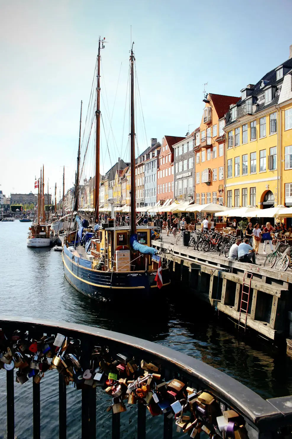 Nyhavn canal in Copenhagen with love locks on a railing, sailing ships, and colorful waterfront buildings