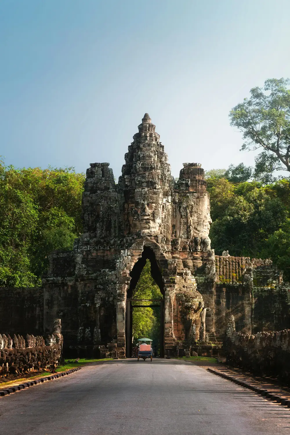 South Gate of Angkor Thom with massive stone face towers and tuk-tuk passing through archway, Siem Reap, Cambodia