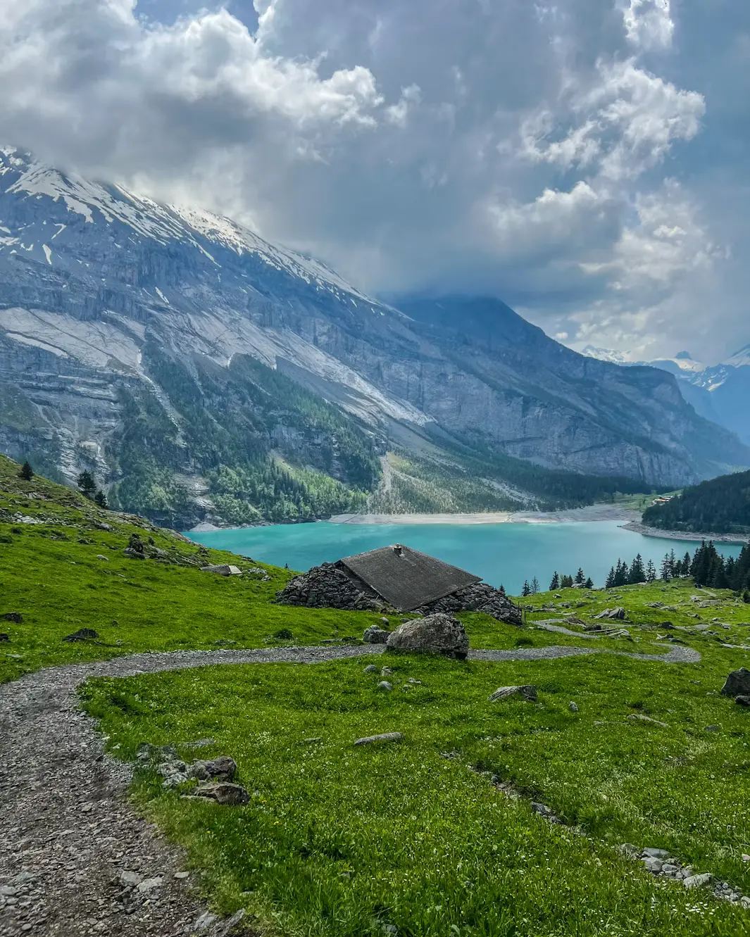Turquoise alpine lake surrounded by green meadows and rocky mountains, Switzerland