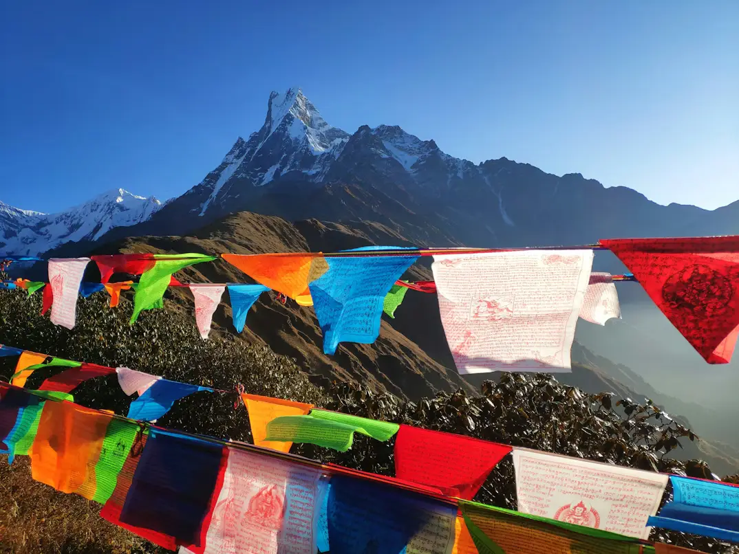 Colorful Buddhist prayer flags across a mountain pass with the Machapuchare (Fishtail) peak in the background, Nepal