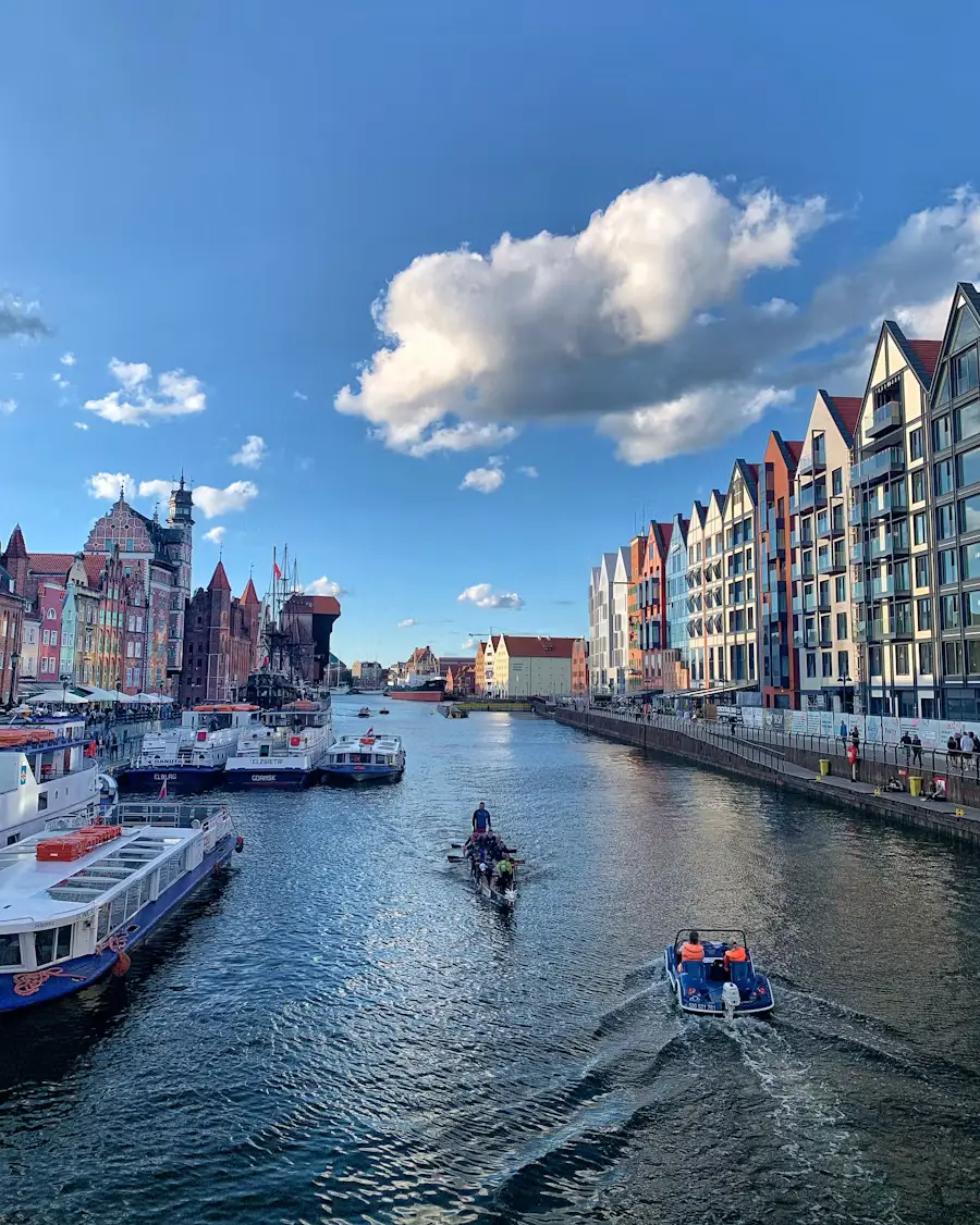 Picturesque Polish canal lined with colorful historic buildings and boats under a bright blue sky.
