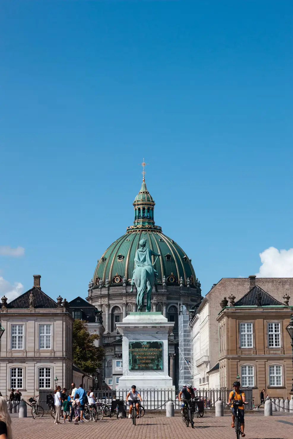 Frederik's Church dome and a statue in Copenhagen with cyclists passing by