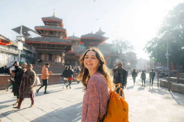 Woman with backpack smiling at Durbar Square with traditional temples, Kathmandu, Nepal