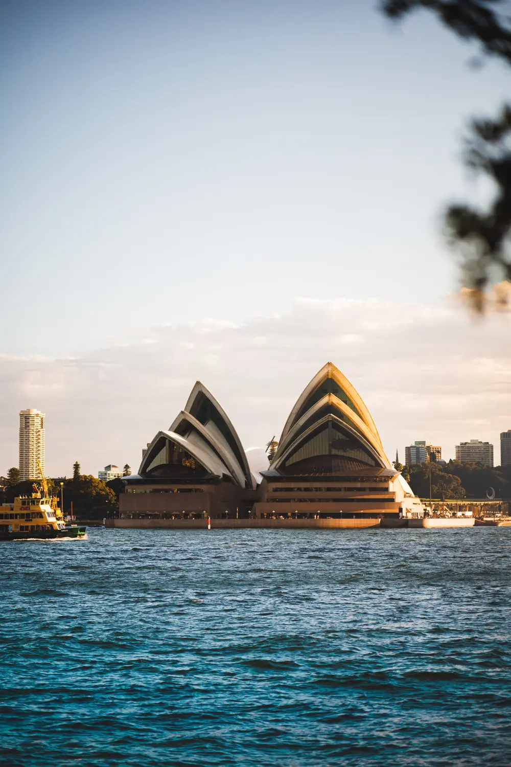 Sydney Opera House at golden hour viewed from the harbour with ferries passing by