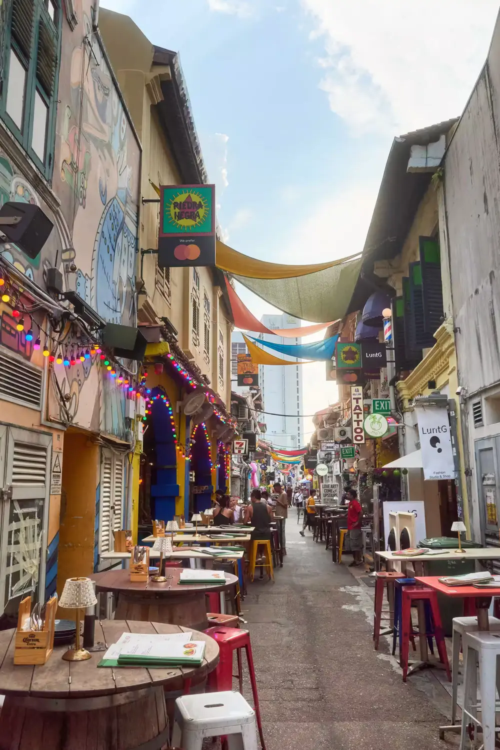 Bustling Haji Lane narrow street with colorful shopfronts outdoor dining and hanging decorations Kampong Glam Singapore