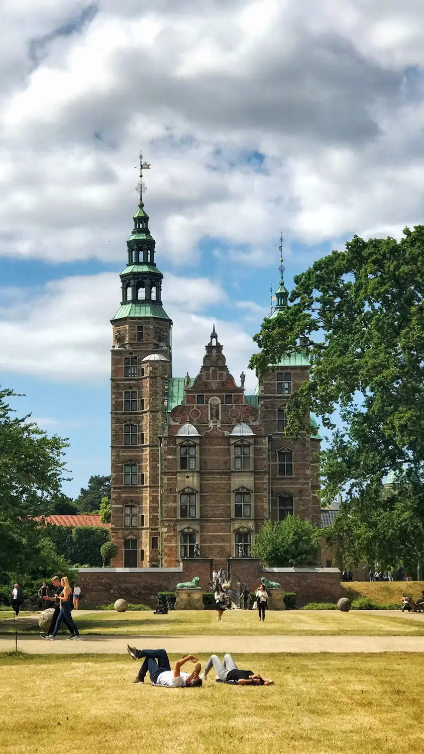 Rosenborg Castle in Copenhagen viewed across a lawn with people relaxing on the grass
