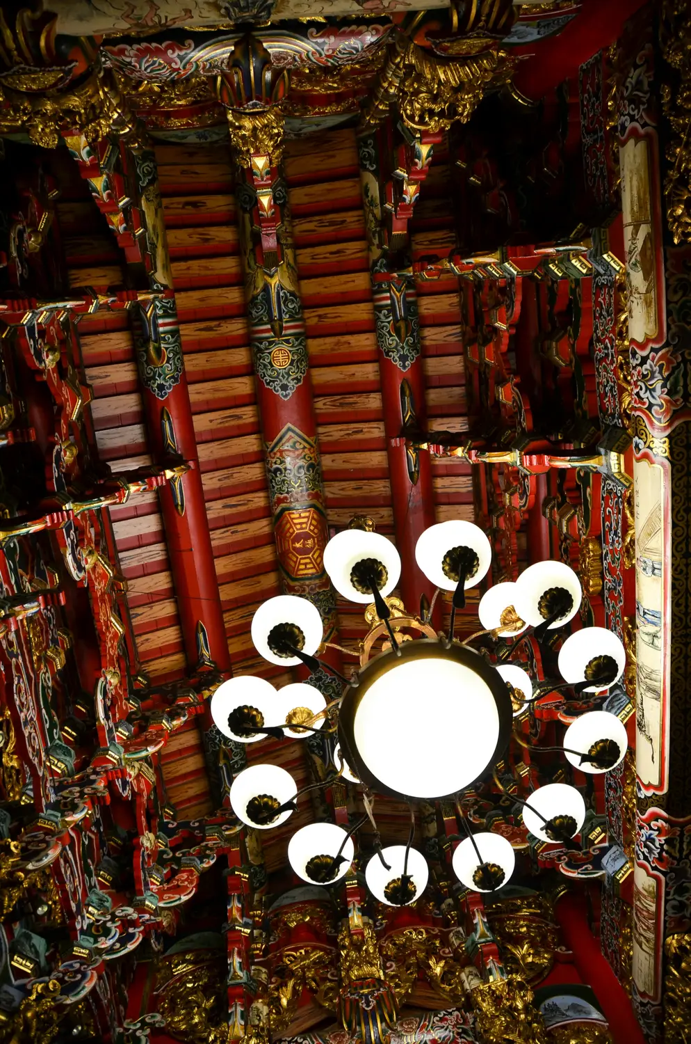 Ornate red and gold carved temple ceiling with a circular hanging lantern chandelier in Taiwanh a circular hanging lantern chandelier in Taiwan