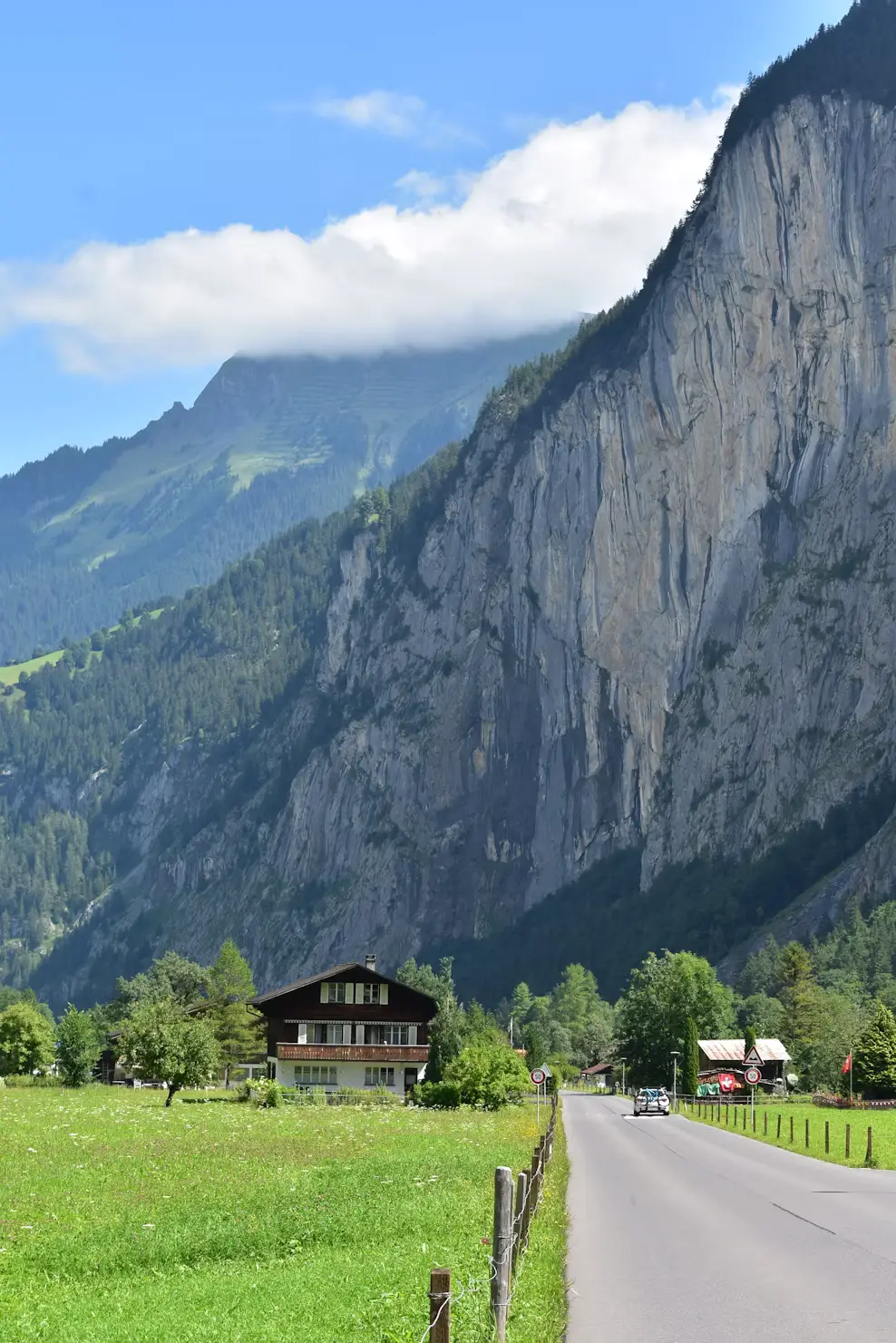 Country road beside a chalet with steep cliffs and waterfalls, Lauterbrunnen Valley, Switzerland