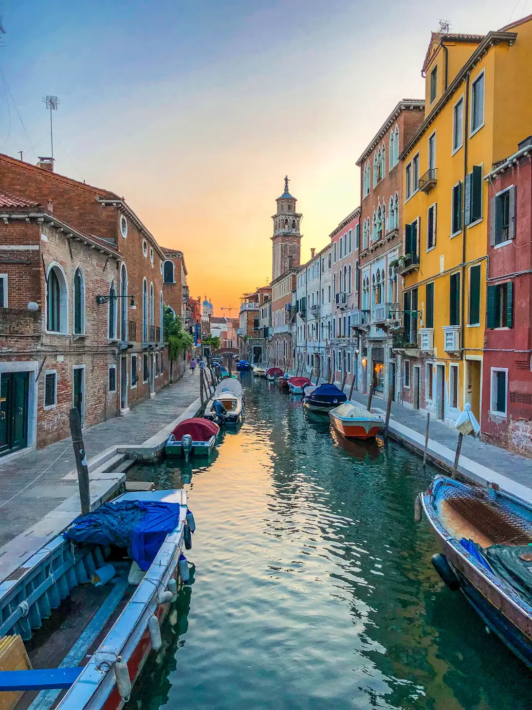 Venice canal lined with pastel buildings glowing at sunset