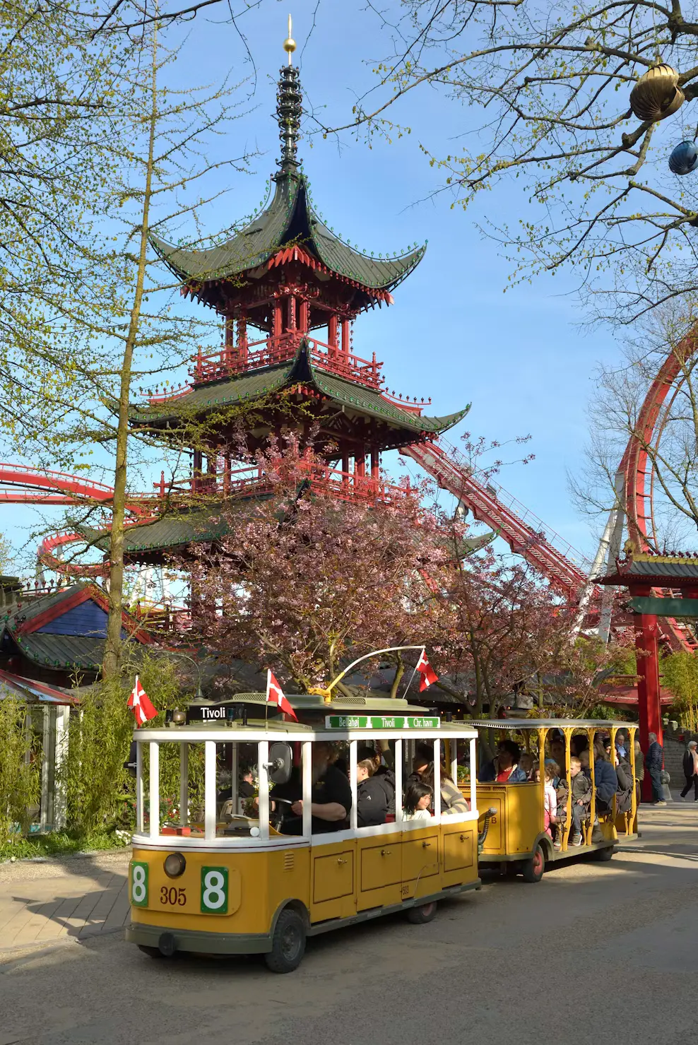 Pagoda tower and roller coaster at Tivoli Gardens amusement park in Copenhagen with a vintage tram in the foreground