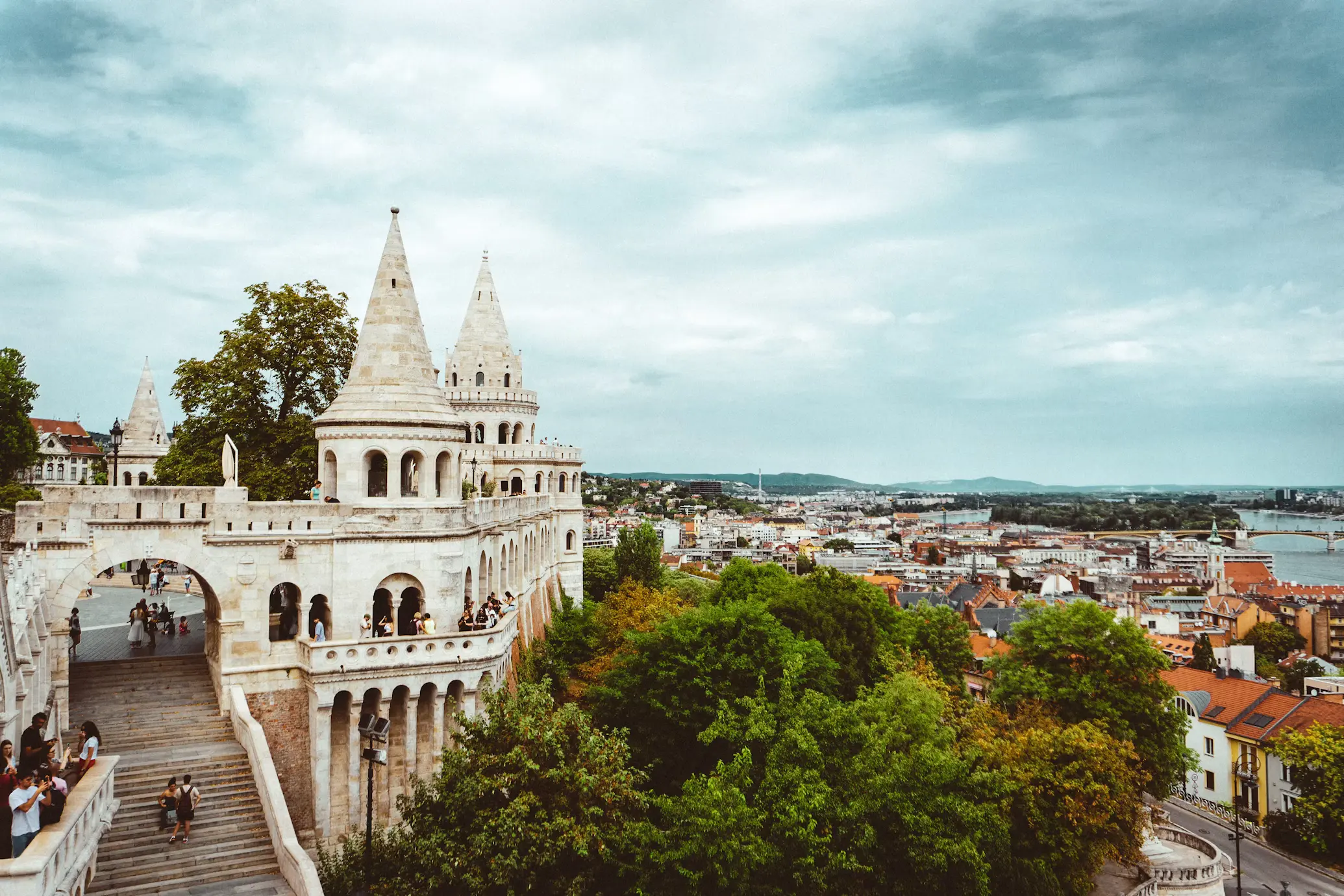 White stone towers and terraces overlooking Budapest under cloudy skies.