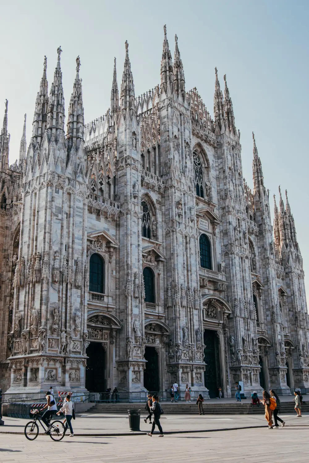 Milan Cathedral's white Gothic spires and facade against a blue sky