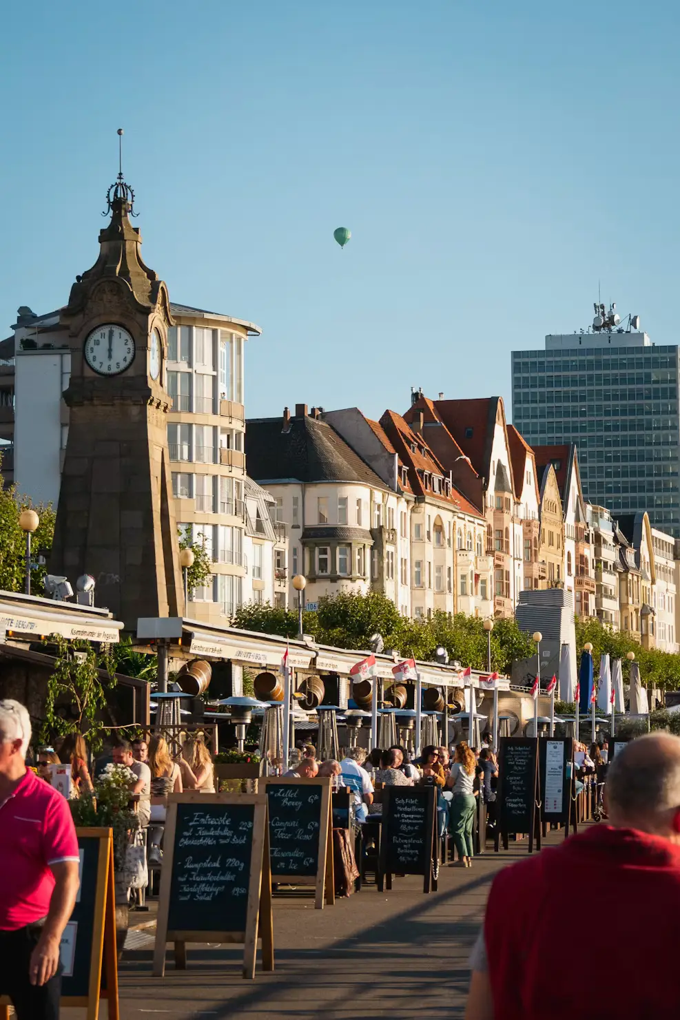 Historic clock tower and outdoor cafes along a lively promenade