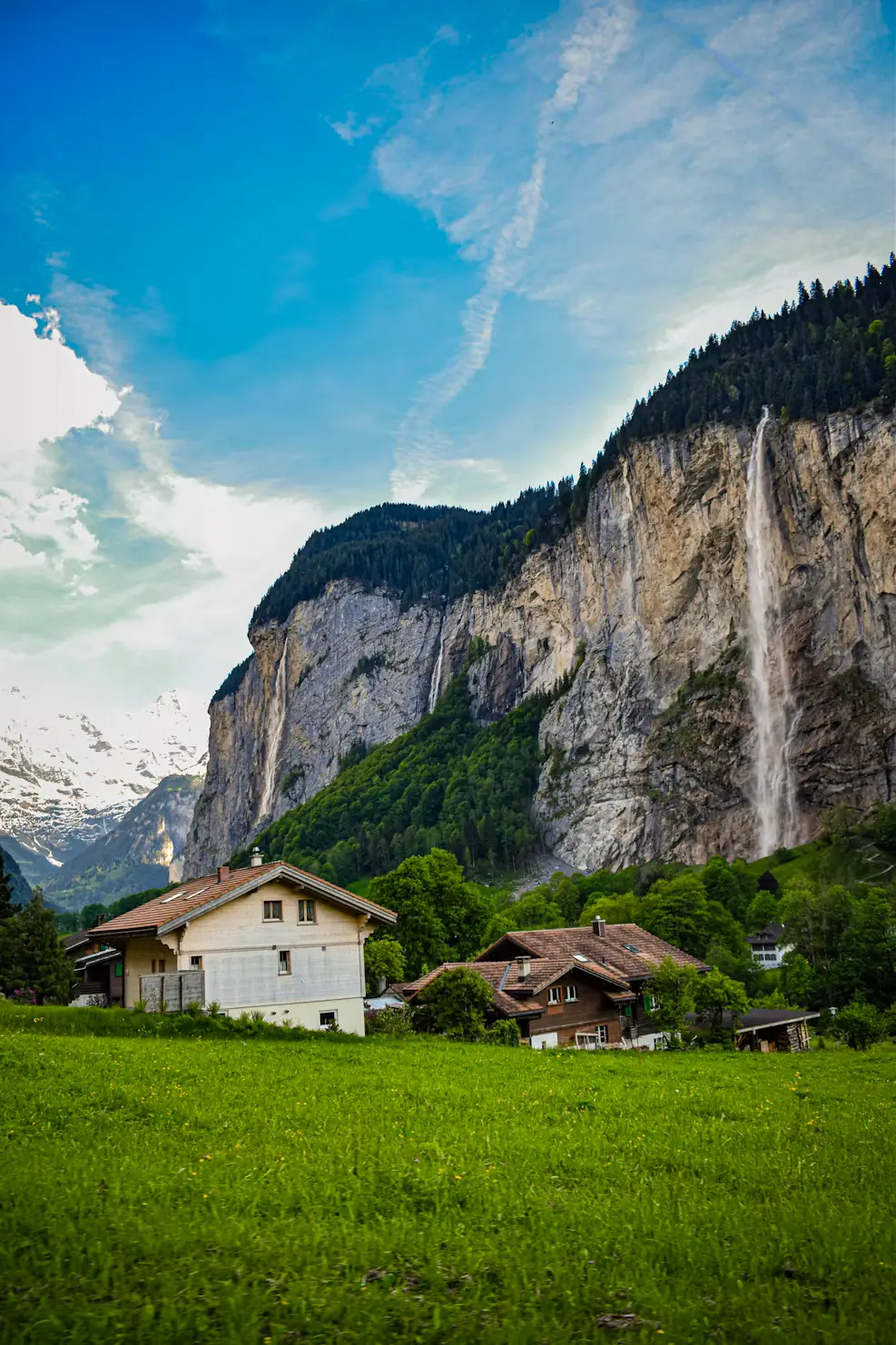 Chalet in a green valley with waterfalls streaming down steep cliffs, Lauterbrunnen, Switzerland