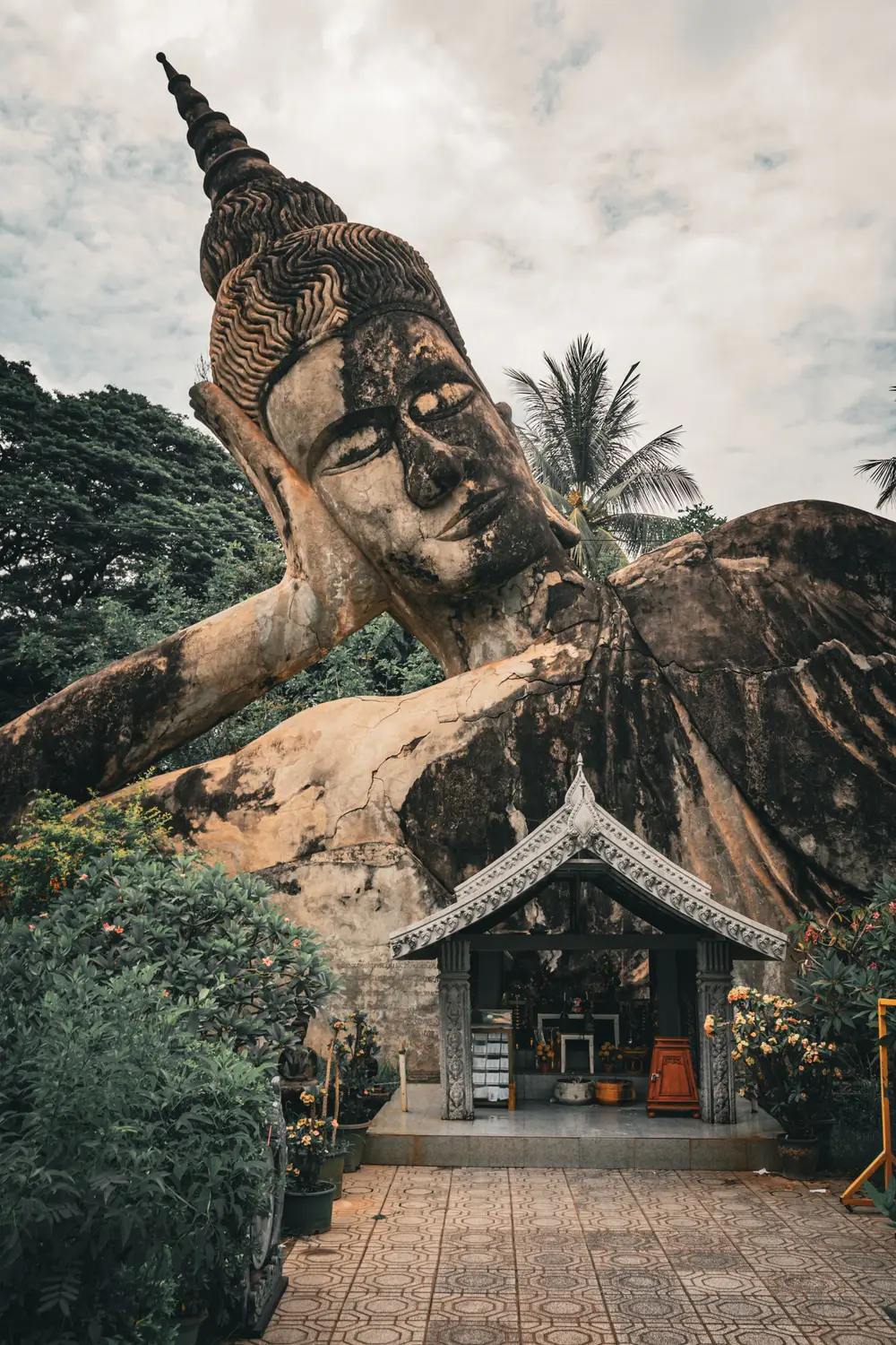 Large reclining Buddha statue and a stupa among trees at Buddha Park near Vientiane, Laos.