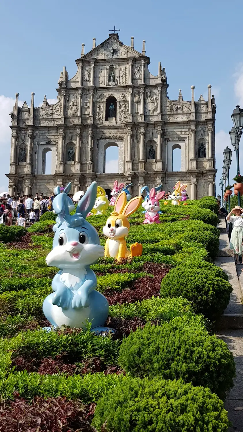 Ruins of St. Paul's facade with decorative rabbit statues in the garden foreground, Macau
