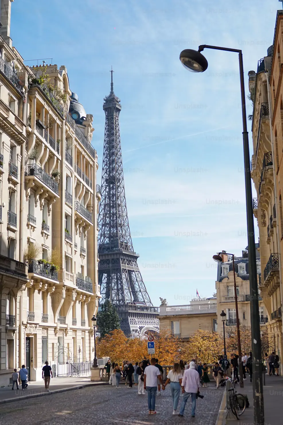 Parisian street with a lamppost and the Eiffel Tower visible between buildings