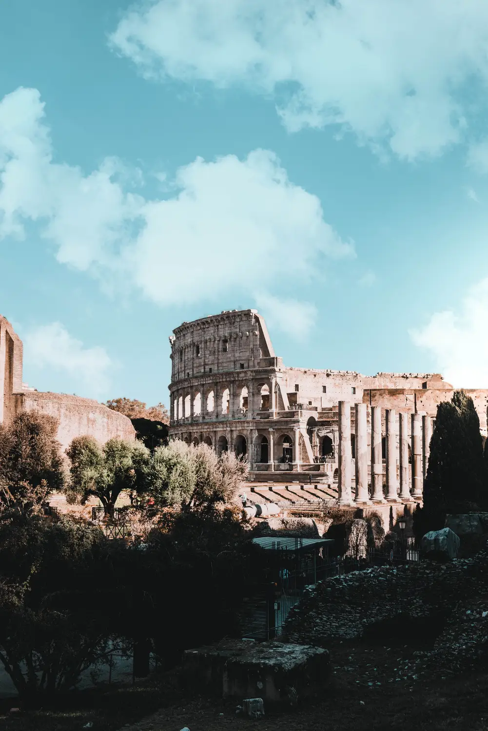 Ancient ruins of the Roman Forum with the Colosseum visible in the background