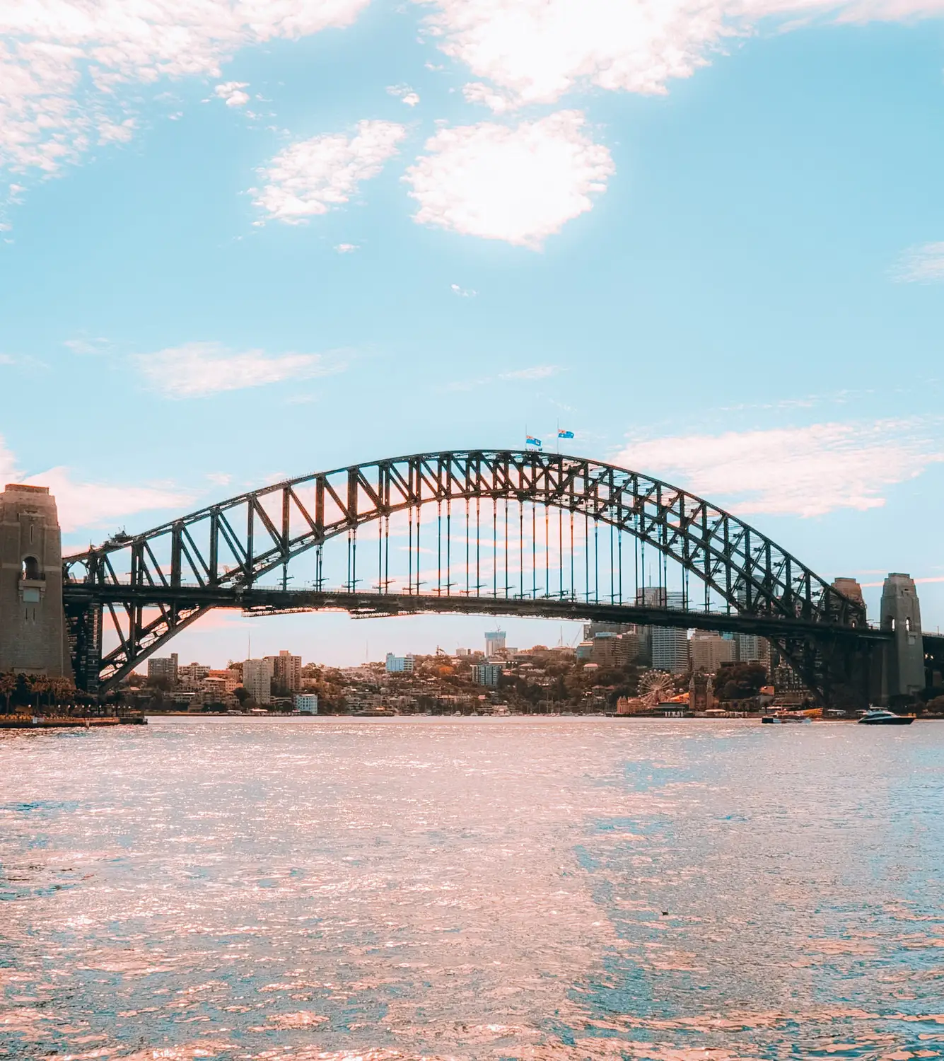 Sydney Harbour Bridge silhouetted against a pink sunset sky over the water