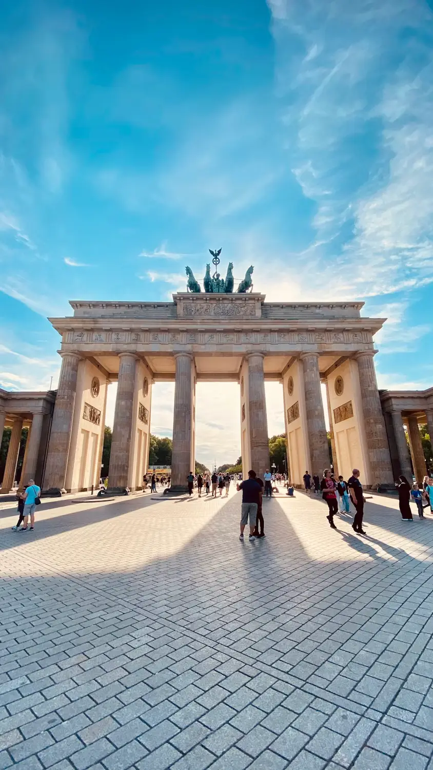 Brandenburg Gate in Berlin with pedestrians walking across the plaza
